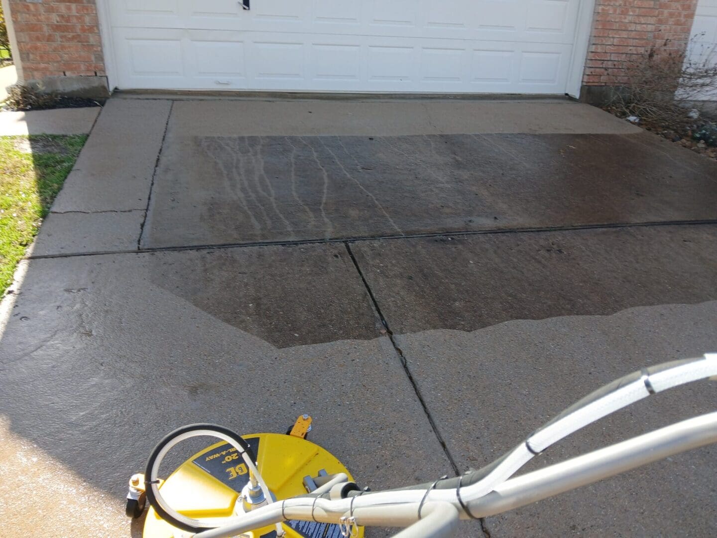 A person is cleaning the driveway with a power washer.