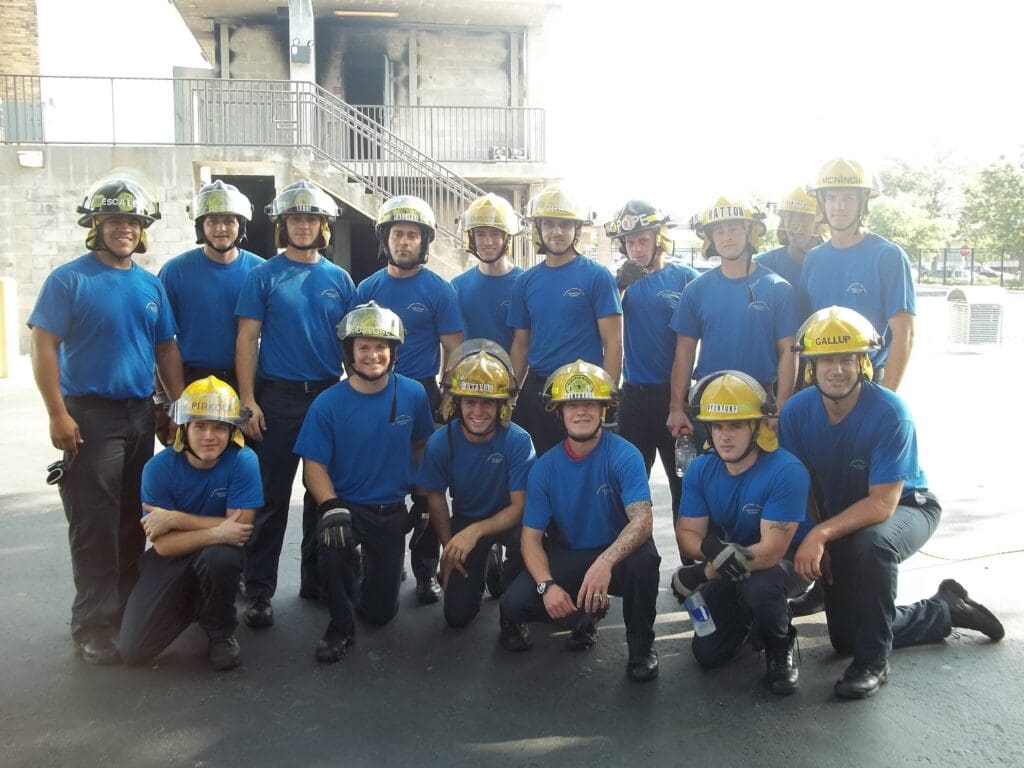 Group of firefighters posing in blue uniforms and helmets.