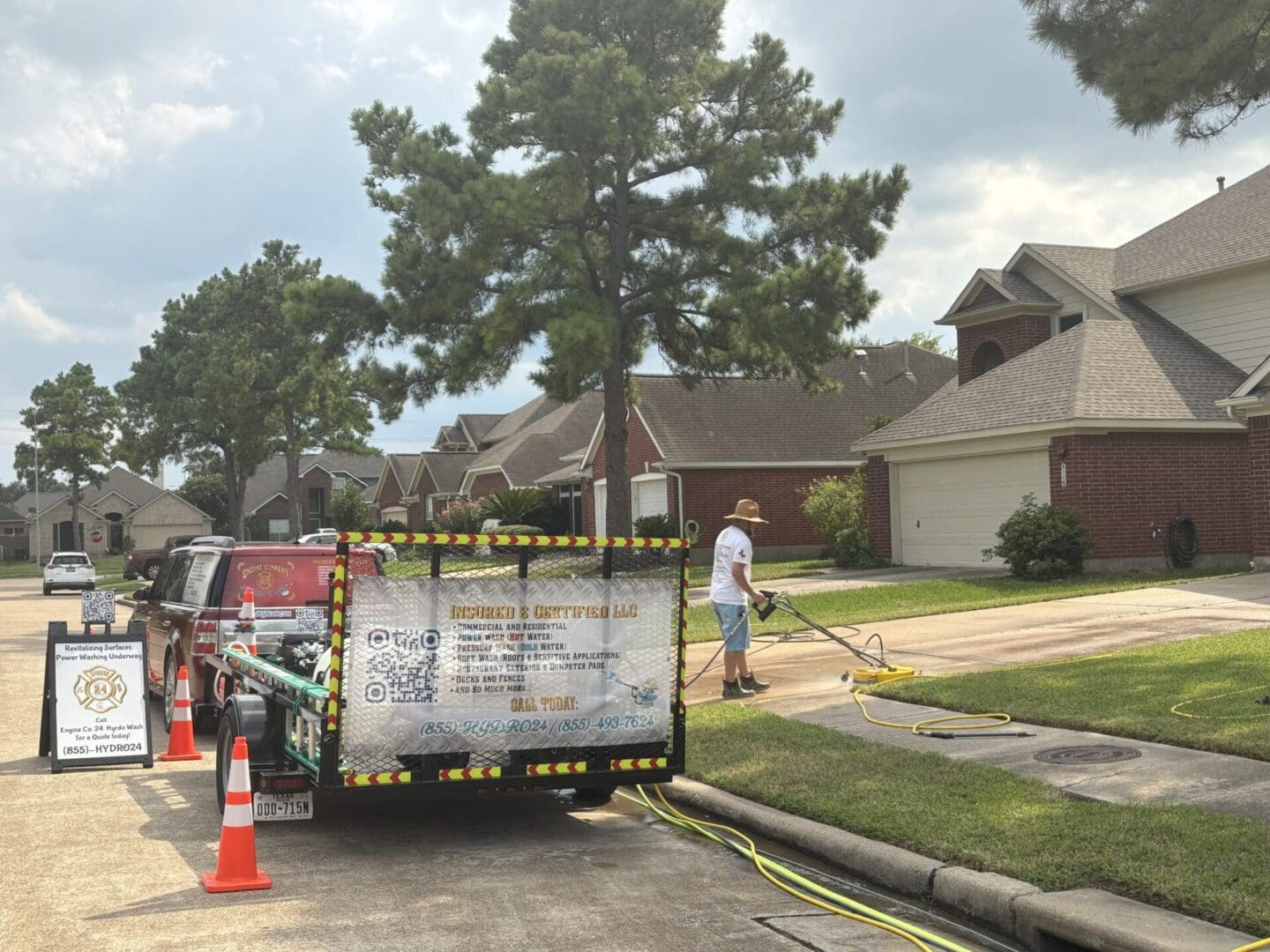 A man pressure washing a house driveway on a sunny day.