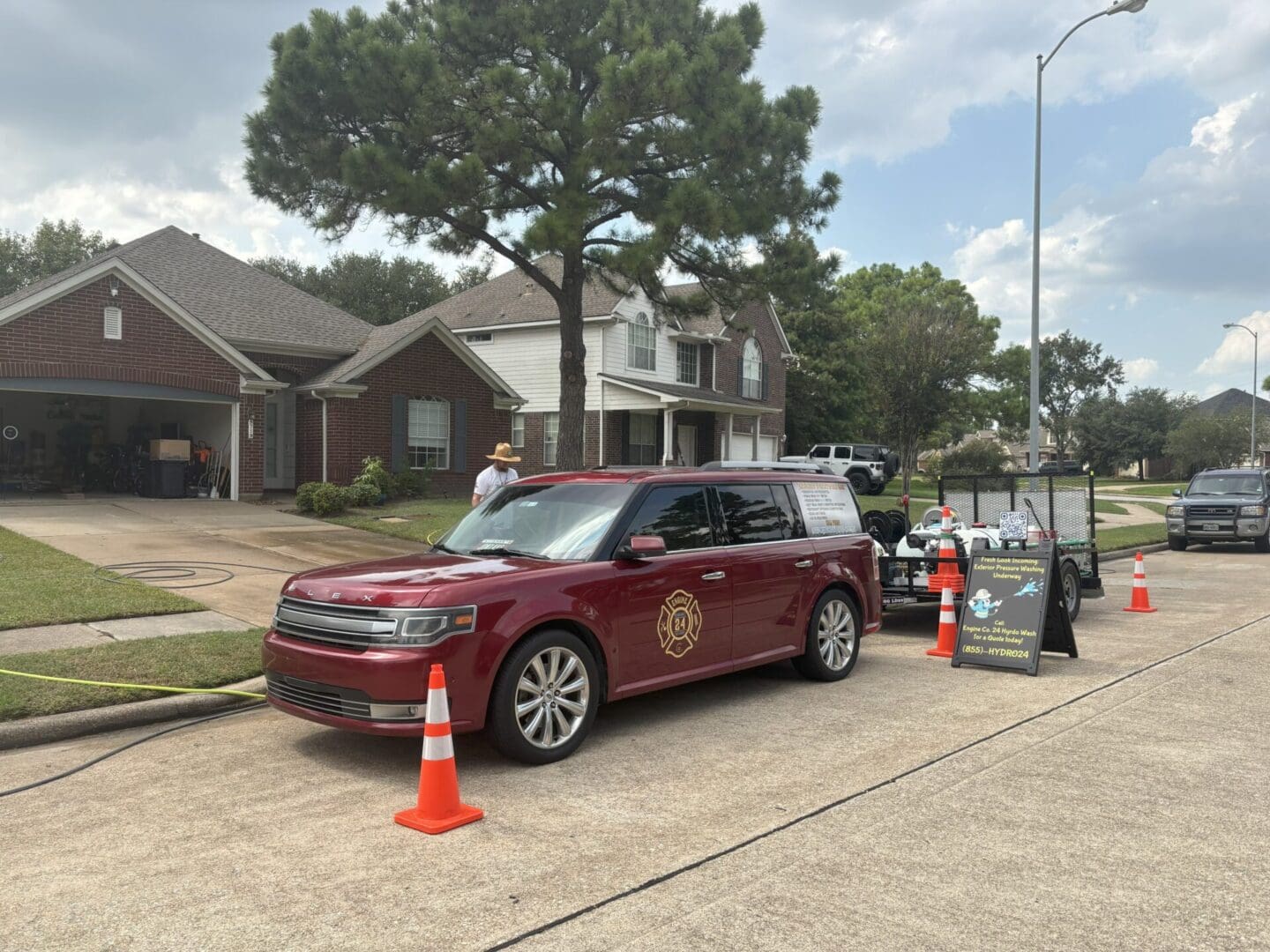 A vintage red car parked on a suburban street near traffic cones.