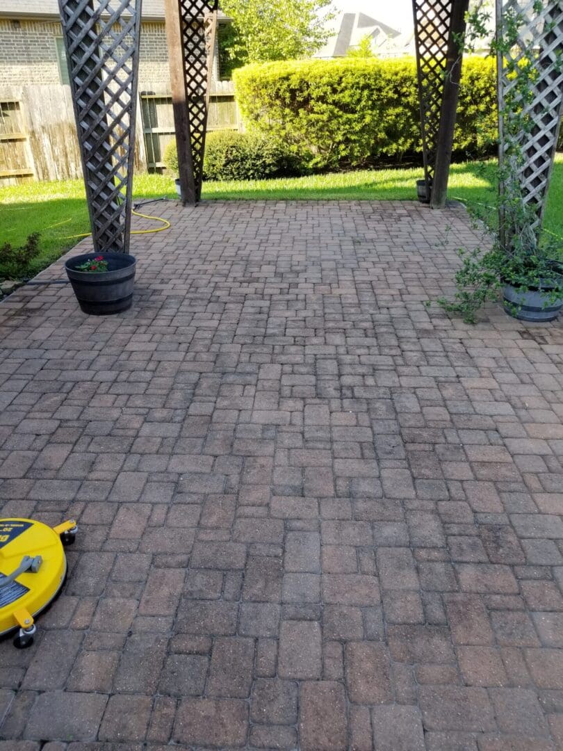 A brick patio with a pressure washer in use.