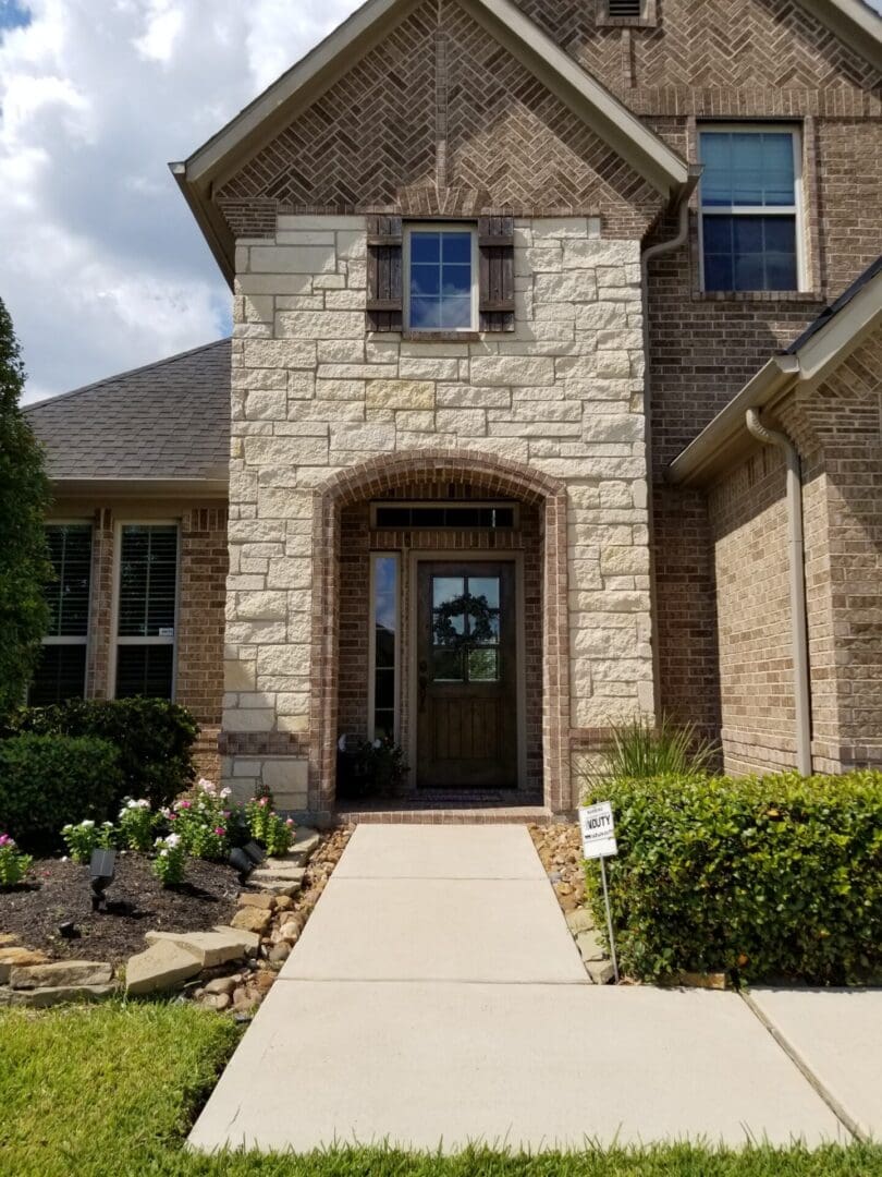 Stone house entrance with wooden door and landscaped garden.