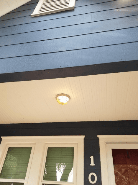 Exterior ceiling light above a doorway on a dark blue house.