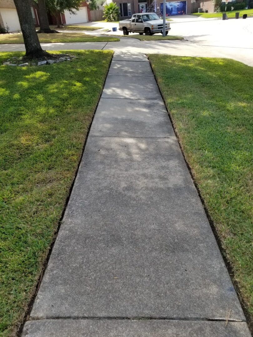 Concrete sidewalk bordered by green grass on both sides.