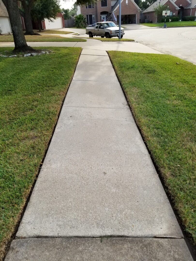 Concrete sidewalk flanked by green grass on both sides.