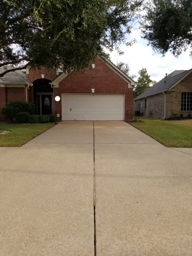 Suburban brick house with a clean driveway and attached garage.