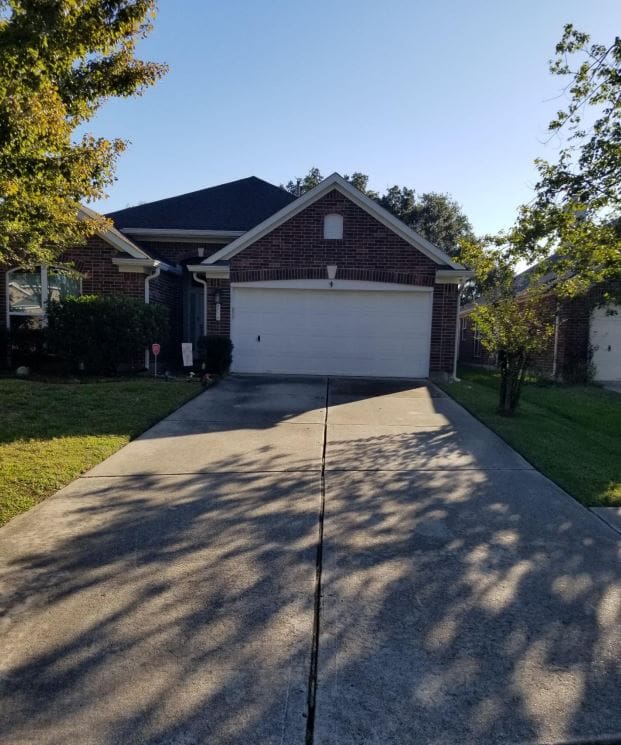 A suburban brick house with a two-car garage and a concrete driveway.