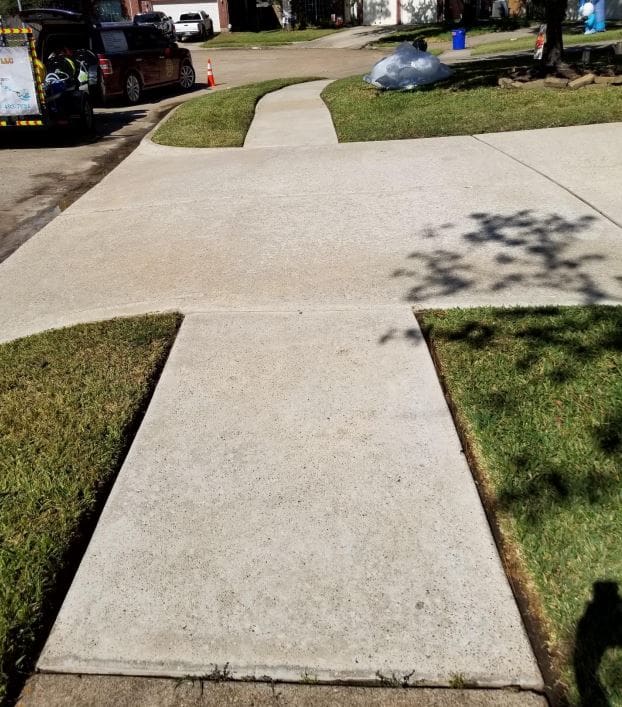 Concrete sidewalks with grass on both sides under sunlight.