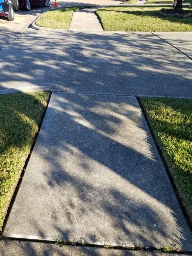 Shadow patterns on a sidewalk with grassy edges.